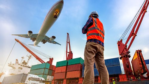 Man working at a warehouse and plane passing by